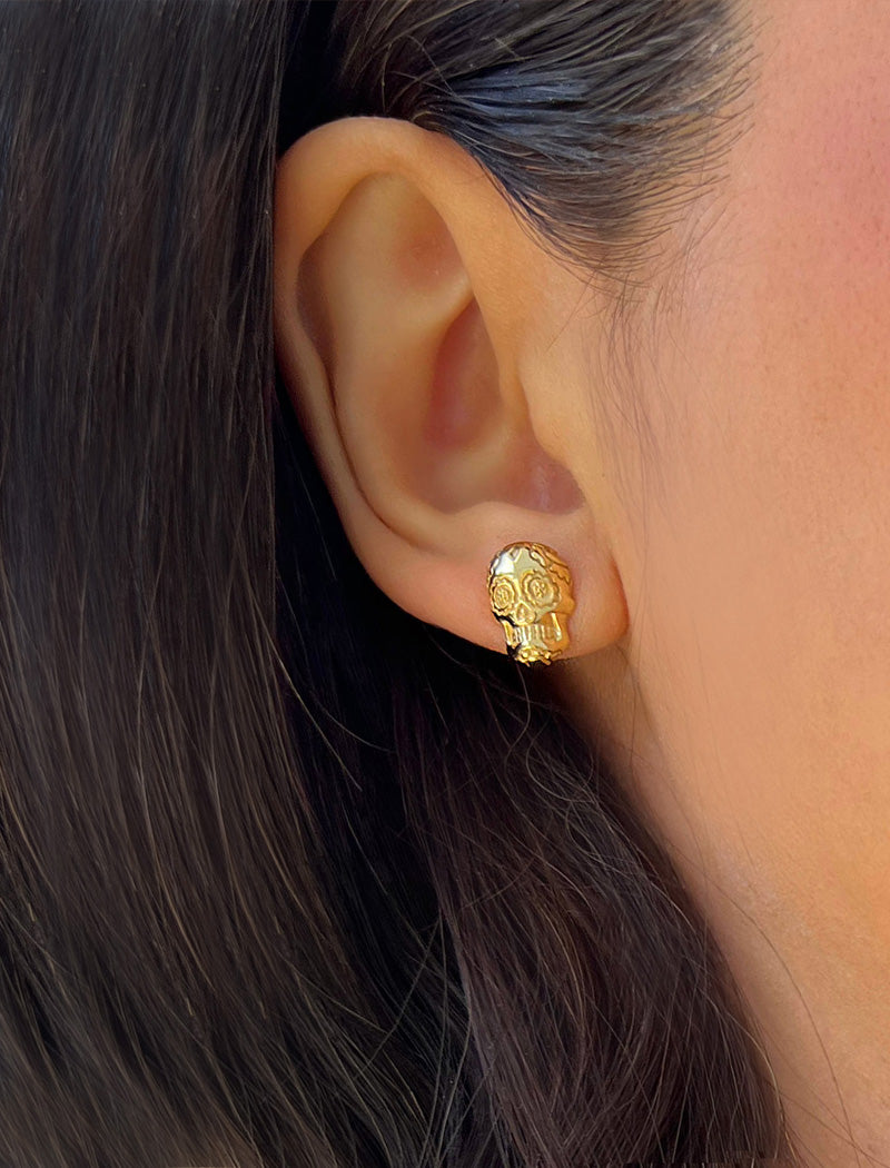 Image Title Woman wearing Culturally inclusive Day Of The Dead Mexican Sugar Skull Stud Earrings in 18K Gold over Sterling Silver by Sonia Hou, a celebrity AAPI Chinese demi-fine jewelry designer. This holiday is also known as Dia De Los Muertos, and can also be worn for Halloween!