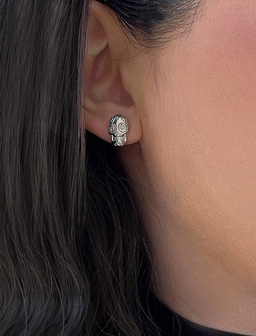 Image Title Woman wearing Culturally inclusive Day Of The Dead Mexican Sugar Skull Stud Earrings in Sterling Silver by Sonia Hou, a celebrity AAPI Chinese demi-fine jewelry designer. This holiday is also known as Dia De Los Muertos, and can also be worn for Halloween!