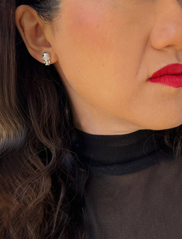 Image Title Woman wearing Culturally inclusive Day Of The Dead Mexican Sugar Skull Stud Earrings in Sterling Silver by Sonia Hou, a celebrity AAPI Chinese demi-fine jewelry designer. This holiday is also known as Dia De Los Muertos, and can also be worn for Halloween!