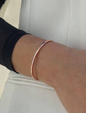 Female model wearing adjustable minimalist simple Success Thin Cuff Chunky Bold Layering Stacking Statement 2 Way convertible Bangle Cuff Open Bracelet in 18K Rose Gold Vermeil with 925 sterling silver base by Sonia Hou, a celebrity AAPI Chinese demi-fine fashion costume jewelry designer