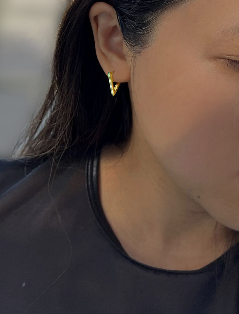 Female model wearing ACHIEVE TRIANGLE GEOMETRIC HUGGIE EARRINGS IN 18K GOLD VERMEIL With Sterling Silver base by Sonia Hou Jewelry