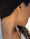 A close-up side profile of a woman wearing a small silver chevron hoop earring. ACHIEVE TRIANGLE GEOMETRIC HUGGIE EARRINGS IN  Sterling Silver by Sonia Hou Jewelry