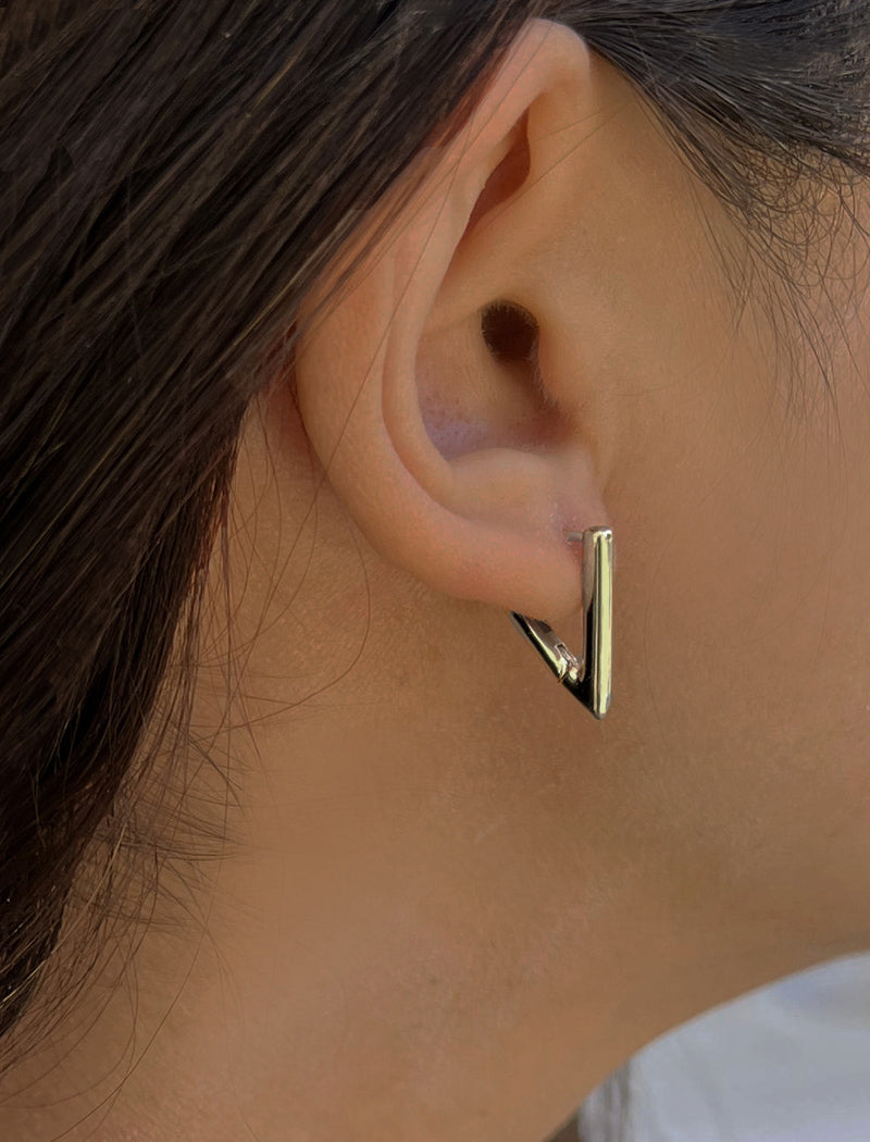 Female model wearing ACHIEVE TRIANGLE GEOMETRIC HUGGIE EARRINGS in Sterling Silver by Sonia Hou Jewelry