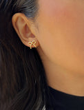 Female model wearing Holiday Coquette Bow Festive Christmas Stud Earrings in 18K Gold Over With Sterling Silver by AAPI Celebrity Jewelry Designer Sonia Hou 