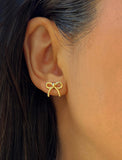 Female model wearing Holiday Coquette Bow Festive Christmas Stud Earrings in 18K Gold Over With Sterling Silver by AAPI Celebrity Jewelry Designer Sonia Hou 