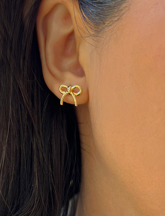 Female model wearing Holiday Coquette Bow Festive Christmas Stud Earrings in 18K Gold Over With Sterling Silver by AAPI Celebrity Jewelry Designer Sonia Hou 