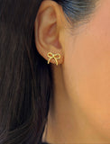 Female model wearing Holiday Coquette Bow Festive Christmas Stud Earrings in 18K Gold Over With Sterling Silver by AAPI Celebrity Jewelry Designer Sonia Hou 