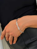 Sterling Silver chain bracelet on a person's wrist against a black background.  Our medium Essential paperclip link chain bracelet is perfect for everyday wear. Designed by AAPI celebrity jewelry designer SONIA HOU.