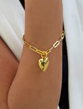 18K Gold Vermeil bracelet with a heart-shaped charm on a wrist against a white background. Fall in love with this timeless statement piece — a modern take on the classic heart motif. Featuring a bold yet feminine Puffy Heart charm suspended from a sleek link chain in 18k gold vermeil, this bracelet radiates effortless confidence and charm. Designed by AAPI celebrity jewelry designer SONIA HOU