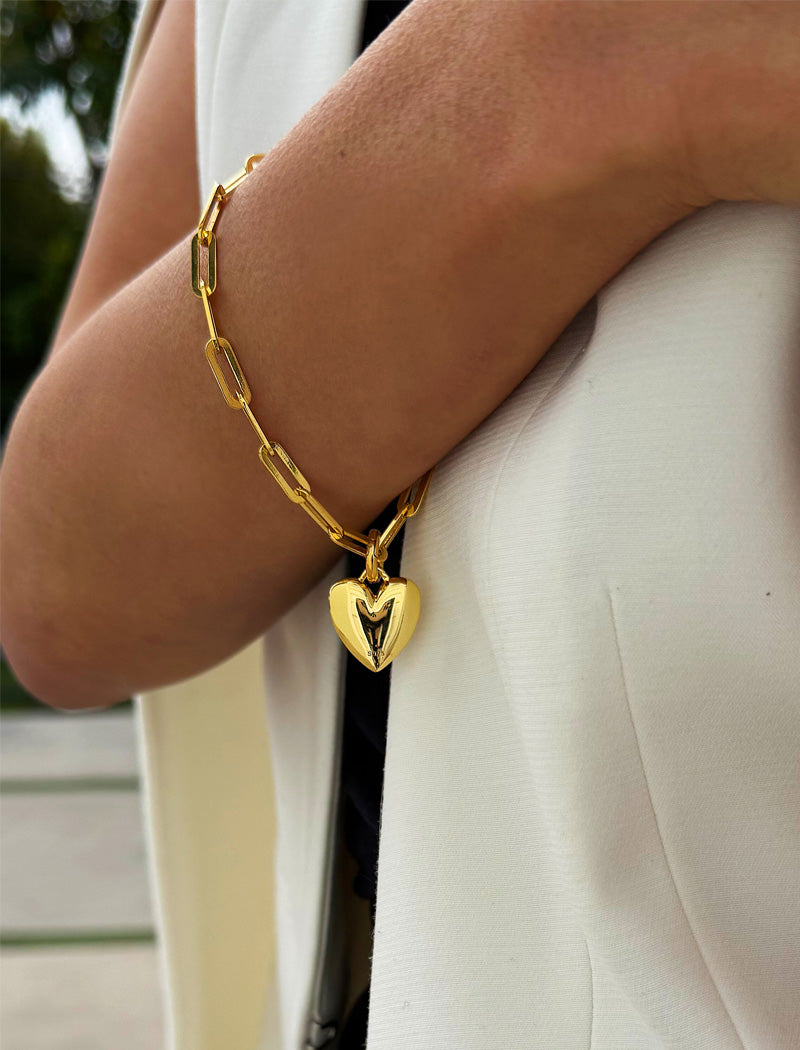 18K Gold Vermeil bracelet with a heart-shaped charm on a wrist against a white background. Fall in love with this timeless statement piece — a modern take on the classic heart motif. Featuring a bold yet feminine Puffy Heart charm suspended from a sleek link chain in 18k gold vermeil, this bracelet radiates effortless confidence and charm. Designed by AAPI celebrity jewelry designer SONIA HOU