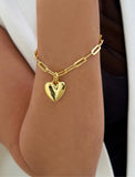 18K Gold Vermeil bracelet with a heart-shaped charm on a wrist against a white background. Fall in love with this timeless statement piece — a modern take on the classic heart motif. Featuring a bold yet feminine Puffy Heart charm suspended from a sleek link chain in 18k gold vermeil, this bracelet radiates effortless confidence and charm. Designed by AAPI celebrity jewelry designer SONIA HOU