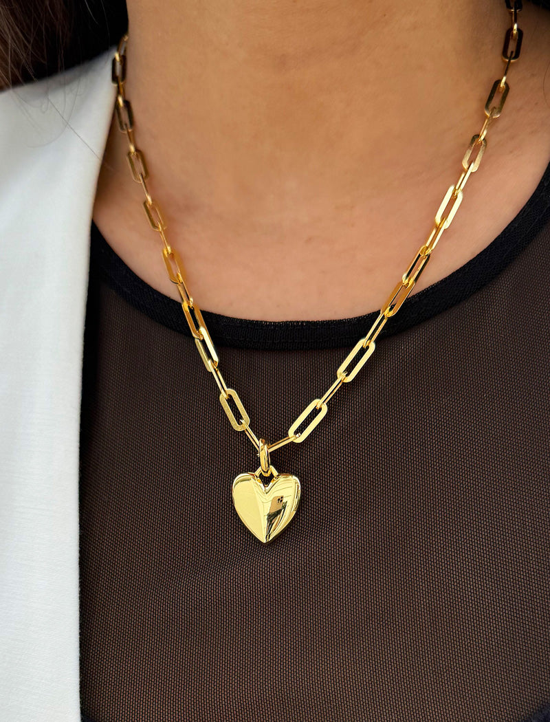18K Gold vermeil chain necklace with a heart pendant worn by a person. Featuring a bold yet feminine Puffy Heart charm suspended from a sleek link chain, this bracelet radiates effortless confidence and charm. Designed to symbolize love, self-expression, and empowerment, the puffy heart serves as a daily reminder to lead with compassion and strength — Designed by AAPI celebrity jewelry designer SONIA HOU.
