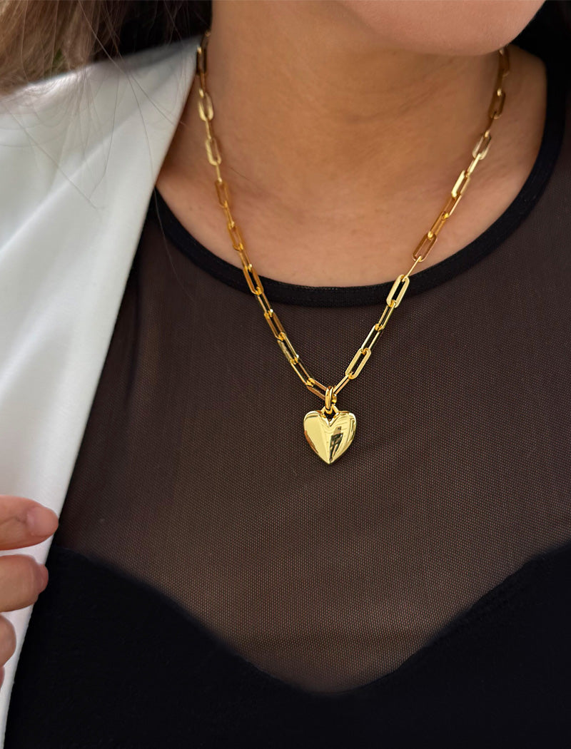 18K Gold vermeil chain necklace with a heart pendant worn by a person. Featuring a bold yet feminine Puffy Heart charm suspended from a sleek link chain, this bracelet radiates effortless confidence and charm. Designed to symbolize love, self-expression, and empowerment, the puffy heart serves as a daily reminder to lead with compassion and strength — Designed by AAPI celebrity jewelry designer SONIA HOU.
