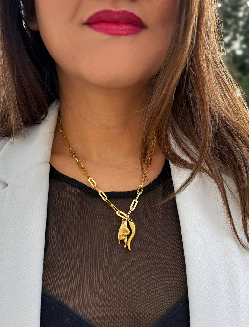 Inspired by centuries-old Italian tradition, this photo showcases a person wearing a modern chain pendant necklace with the Italian Horn —also known as the cornicello—and Italian Hand a powerful emblem of protection, strength, and good fortune. Made of 18K Gold PVD Stainless Steel (waterproof).  Designed for everyone who values inclusivity, diversity, and meaning, it’s a timeless statement of strength and modern style. It's perfect for everyday wear. Designed by AAPI celebrity jewelry designer SONIA HOU.