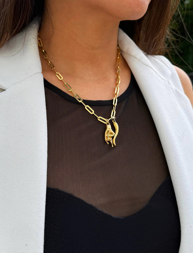 Inspired by centuries-old Italian tradition, this photo showcases a person wearing a modern chain pendant necklace with the Italian Horn —also known as the cornicello—and Italian Hand a powerful emblem of protection, strength, and good fortune. Made of 18K Gold PVD Stainless Steel (waterproof).  Designed for everyone who values inclusivity, diversity, and meaning, it’s a timeless statement of strength and modern style. It's perfect for everyday wear. Designed by AAPI celebrity jewelry designer SONIA HOU.