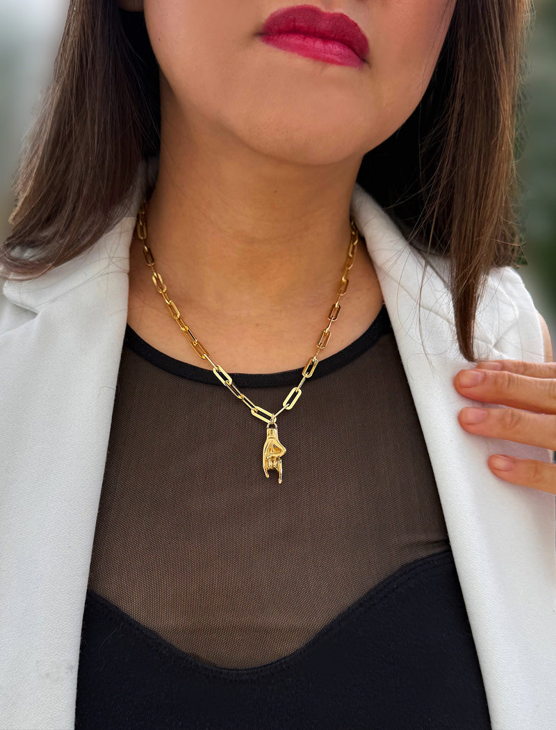 Person wearing a waterproof Italian Hand pendant necklace—also known as Mano Cornuta or the “Horned Hand” amulet in 18K Gold PVD stainless steel.  Designed for everyone who values inclusivity, diversity, and meaning, it’s a timeless statement of strength and modern style. It's perfect for everyday wear. Designed by AAPI celebrity jewelry designer SONIA HOU.