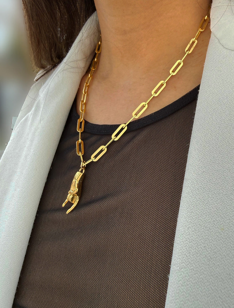 Person wearing a waterproof Italian Hand pendant necklace—also known as Mano Cornuta or the “Horned Hand” amulet in 18K Gold PVD stainless steel.  Designed for everyone who values inclusivity, diversity, and meaning, it’s a timeless statement of strength and modern style. It's perfect for everyday wear. Designed by AAPI celebrity jewelry designer SONIA HOU.