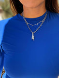 Person wearing a silver stainless steel Italian Hand pendant—also known as Mano Cornuta or the “Horned Hand” amulet.  Designed for everyone who values inclusivity, diversity, and meaning, it’s a timeless statement of strength and modern style. It's perfect for everyday wear. Designed by AAPI celebrity jewelry designer SONIA HOU.