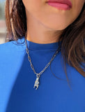 Person wearing a silver stainless steel Italian Hand pendant—also known as Mano Cornuta or the “Horned Hand” amulet.  Designed for everyone who values inclusivity, diversity, and meaning, it’s a timeless statement of strength and modern style. It's perfect for everyday wear. Designed by AAPI celebrity jewelry designer SONIA HOU.