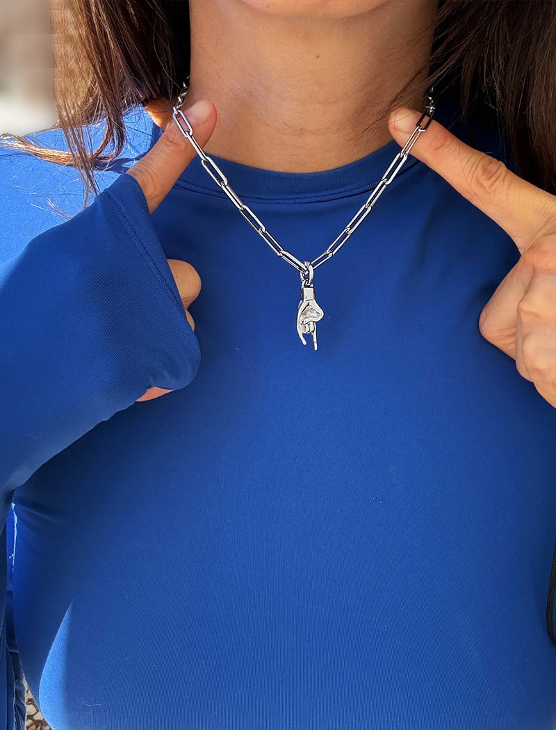 Person wearing a silver stainless steel Italian Hand pendant—also known as Mano Cornuta or the “Horned Hand” amulet.  Designed for everyone who values inclusivity, diversity, and meaning, it’s a timeless statement of strength and modern style. It's perfect for everyday wear. Designed by AAPI celebrity jewelry designer SONIA HOU.