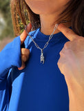 Person wearing a silver stainless steel Italian Hand pendant—also known as Mano Cornuta or the “Horned Hand” amulet.  Designed for everyone who values inclusivity, diversity, and meaning, it’s a timeless statement of strength and modern style. It's perfect for everyday wear. Designed by AAPI celebrity jewelry designer SONIA HOU.