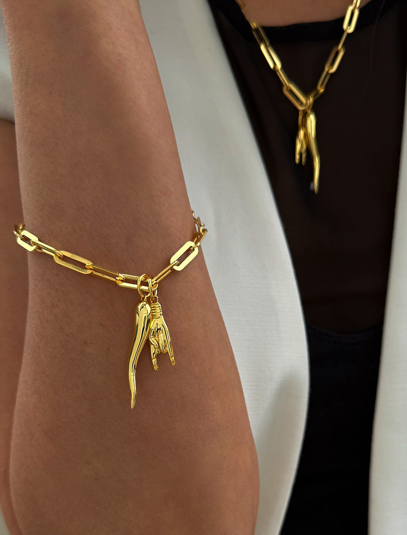 18K Gold vermeil (sterling silver) chain bracelet with a unique pendant on a wrist against a neutral background. Inspired by centuries-old Italian tradition, this modern chain bracelet features the Italian horn and hand charm, also known as the cornicello and Mano Cornuta — a powerful symbol of protection, good fortune, and strength. Designed by AAPI celebrity jewelry designer SONIA HOU.
