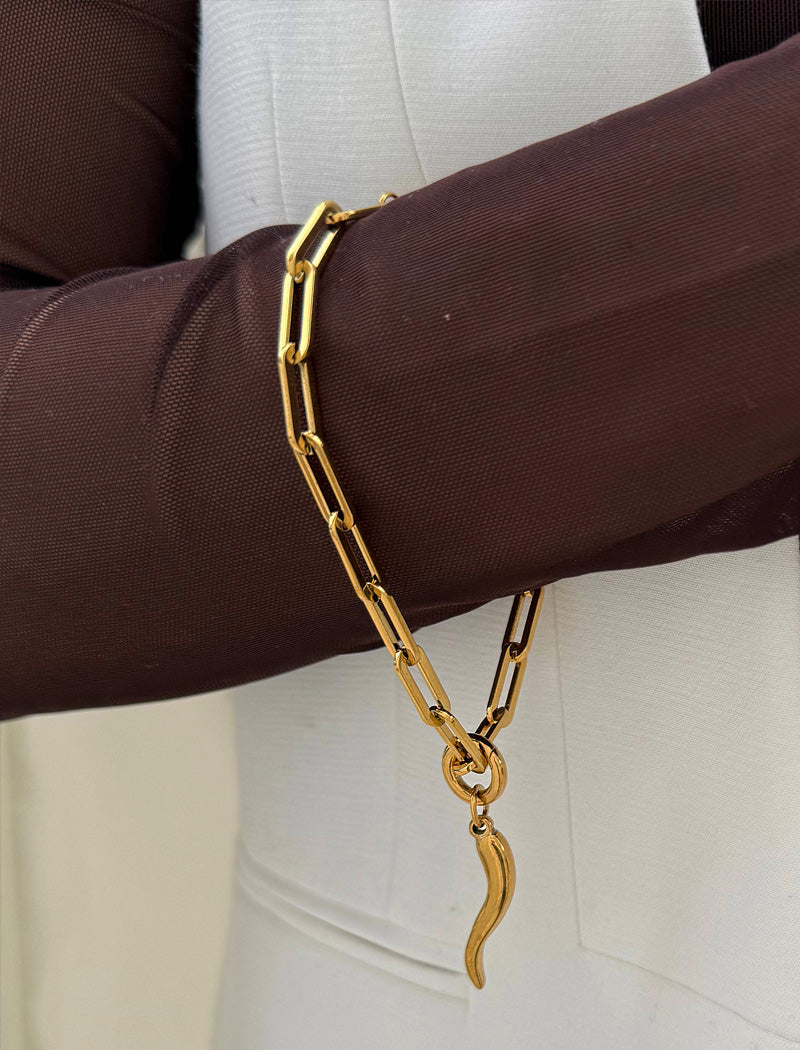 18K Gold stainless steel (waterproof) chain bracelet with a unique clasp worn by a person in a brown long-sleeve shirt. Inspired by centuries-old Italian tradition, this modern chain bracelet features the Italian horn charm, also known as the cornicello — a powerful symbol of protection, good fortune, and strength. Designed by AAPI celebrity jewelry designer SONIA HOU.
