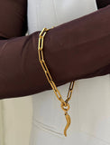 18K Gold stainless steel (waterproof) chain bracelet with a unique clasp worn by a person in a brown long-sleeve shirt. Inspired by centuries-old Italian tradition, this modern chain bracelet features the Italian horn charm, also known as the cornicello — a powerful symbol of protection, good fortune, and strength. Designed by AAPI celebrity jewelry designer SONIA HOU.
