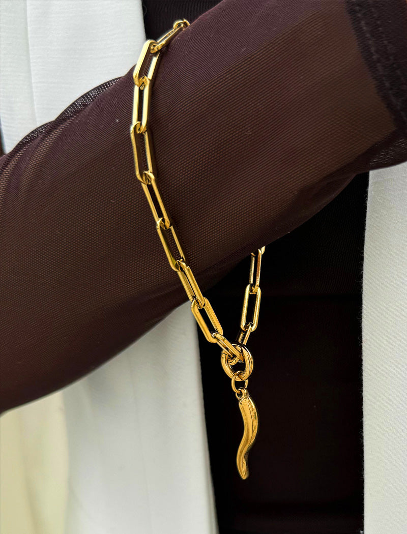 18K Gold stainless steel (waterproof) chain bracelet with a unique clasp worn by a person in a brown long-sleeve shirt. Inspired by centuries-old Italian tradition, this modern chain bracelet features the Italian horn charm, also known as the cornicello — a powerful symbol of protection, good fortune, and strength. Designed by AAPI celebrity jewelry designer SONIA HOU.
