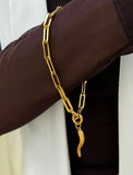 18K Gold stainless steel (waterproof) chain bracelet with a unique clasp worn by a person in a brown long-sleeve shirt. Inspired by centuries-old Italian tradition, this modern chain bracelet features the Italian horn charm, also known as the cornicello — a powerful symbol of protection, good fortune, and strength. Designed by AAPI celebrity jewelry designer SONIA HOU.
