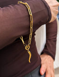 18K Gold stainless steel (waterproof) chain bracelet with a unique clasp worn by a person in a brown long-sleeve shirt. Inspired by centuries-old Italian tradition, this modern chain bracelet features the Italian horn charm, also known as the cornicello — a powerful symbol of protection, good fortune, and strength. Designed by AAPI celebrity jewelry designer SONIA HOU.
