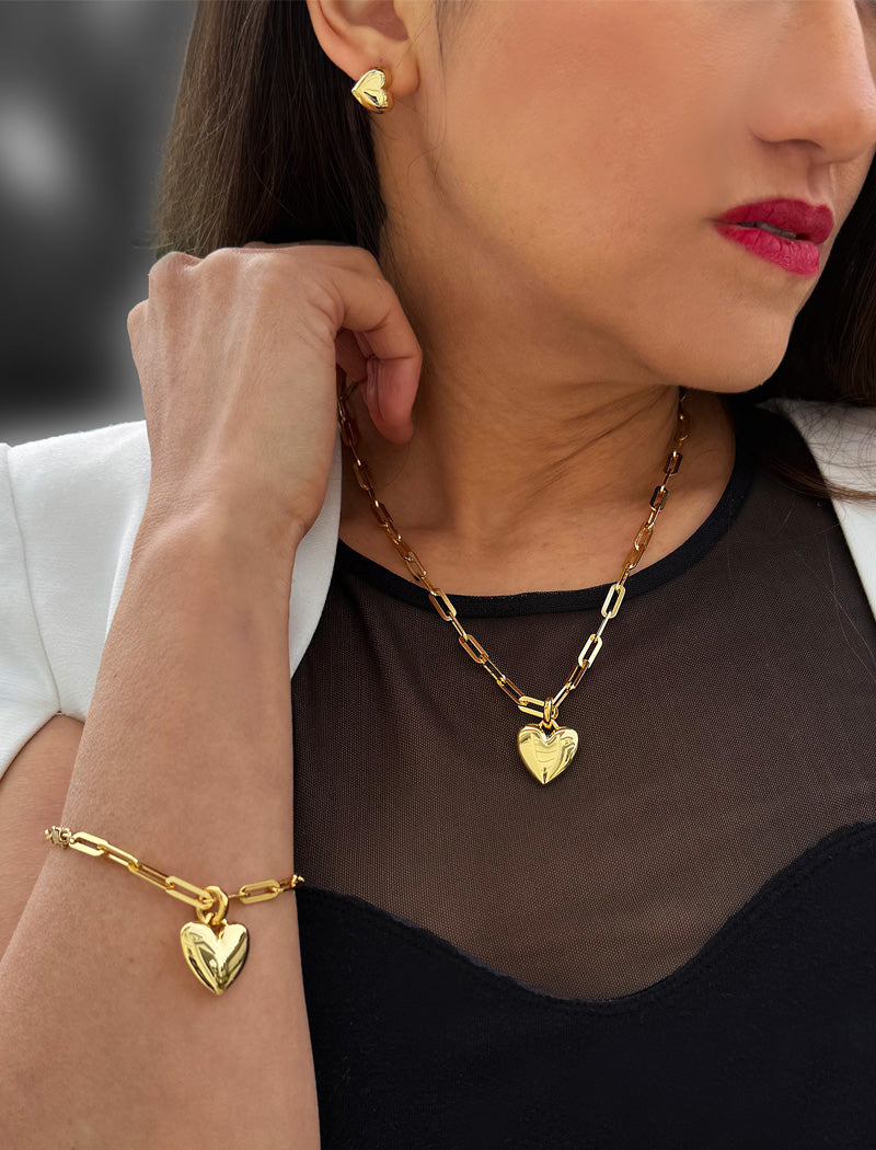 18K Gold vermeil chain necklace with a heart pendant worn by a person. Featuring a bold yet feminine Puffy Heart charm suspended from a sleek link chain, this bracelet radiates effortless confidence and charm. Designed to symbolize love, self-expression, and empowerment, the puffy heart serves as a daily reminder to lead with compassion and strength — Designed by AAPI celebrity jewelry designer SONIA HOU.
