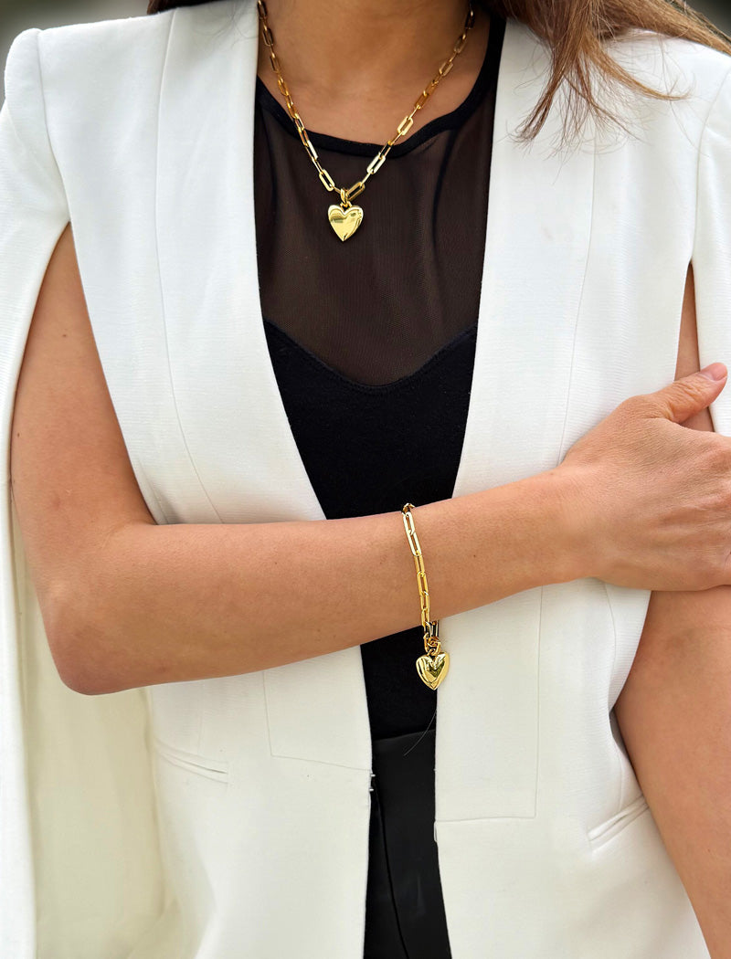 18K Gold vermeil chain necklace with a heart pendant worn by a person. Featuring a bold yet feminine Puffy Heart charm suspended from a sleek link chain, this bracelet radiates effortless confidence and charm. Designed to symbolize love, self-expression, and empowerment, the puffy heart serves as a daily reminder to lead with compassion and strength — Designed by AAPI celebrity jewelry designer SONIA HOU.
