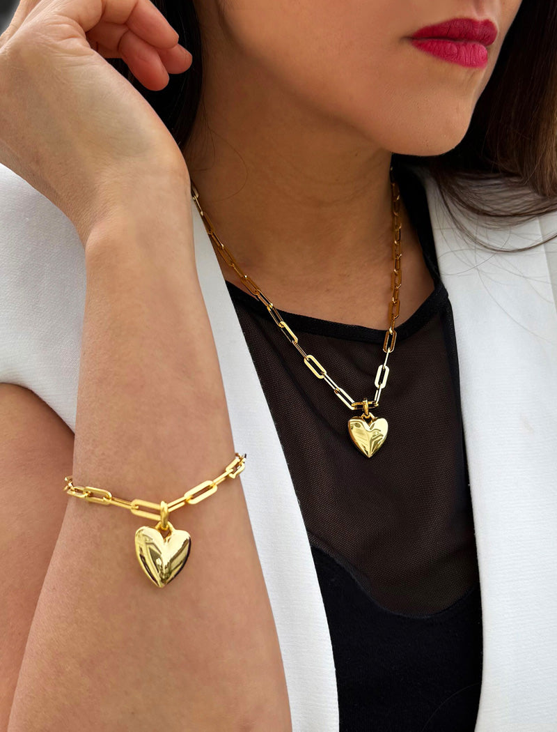 18K Gold vermeil chain necklace with a heart pendant worn by a person. Featuring a bold yet feminine Puffy Heart charm suspended from a sleek link chain, this bracelet radiates effortless confidence and charm. Designed to symbolize love, self-expression, and empowerment, the puffy heart serves as a daily reminder to lead with compassion and strength — Designed by AAPI celebrity jewelry designer SONIA HOU.
