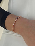 Female model wearing adjustable minimalist simple Success Thin Cuff Chunky Bold Layering Stacking Statement 2 Way convertible Bangle Cuff Open Bracelet in 18K rose gold vermeil with 925 sterling silver base by Sonia Hou, a celebrity AAPI Chinese demi-fine fashion costume jewelry designer