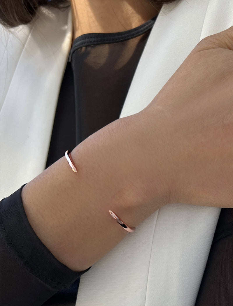 Female model wearing adjustable minimalist simple Success Thin Cuff Chunky Bold Layering Stacking Statement 2 Way convertible Bangle Cuff Open Bracelet in 18K rose gold vermeil with 925 sterling silver base by Sonia Hou, a celebrity AAPI Chinese demi-fine fashion costume jewelry designer