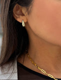 Close-up of a person wearing silver earrings and a necklace. Delicately crafted from sterling silver, these modern Teardrop Earrings are more than a timeless accessory — they’re a symbol of strength, resilience, and beauty. The elegant teardrop shape captures life’s emotions with grace, turning a simple gesture into a statement of empowerment. Designed by AAPI celebrity jewelry designer SONIA HOU.