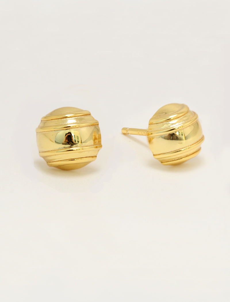 A pair of gold-colored, minimalist tennis ball stud earrings with a ribbed, textured spherical design, shown on a plain light background by Sonia Hou, a celebrity AAPI inclusive demi-fine jewelry designer. Available in 18K Gold Over Sterling Silver, Sterling Silver and 18K Gold PVD Stainless Steel (Waterproof).