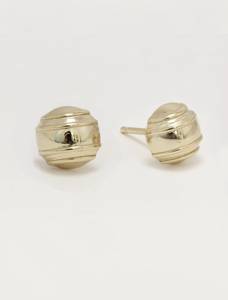 A pair of silver-toned minimalist tennis ball stud earrings with a ribbed, textured spherical design, shown on a plain light gray background by Sonia Hou, a celebrity AAPI inclusive demi-fine jewelry designer. Available in 18K Gold Over Sterling Silver, Sterling Silver and 18K Gold PVD Stainless Steel (Waterproof).