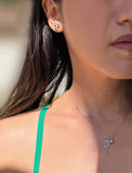 A close-up lifestyle shot of a woman wearing a silver tennis ball and racket pendant necklace and a matching silver tennis ball stud earring. Designed by Sonia Hou, a celebrity AAPI inclusive demi-fine jewelry designer. Available in 18K Gold Over Sterling Silver, Sterling Silver and 18K Gold PVD Stainless Steel (Waterproof).