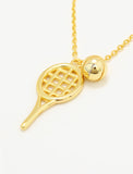 A gold tennis racket and ball pendant necklace on a delicate gold chain, photographed against a clean white background by Sonia Hou, a celebrity AAPI inclusive demi-fine jewelry designer. Available in 18K Gold Over Sterling Silver, Sterling Silver and 18K Gold PVD Stainless Steel (Waterproof).