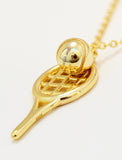 Gold tennis racket pendant necklace with a small gold tennis ball resting on the racket head, shown on a white background by Sonia Hou, a celebrity AAPI inclusive demi-fine jewelry designer. Available in 18K Gold Over Sterling Silver, Sterling Silver and 18K Gold PVD Stainless Steel (Waterproof).