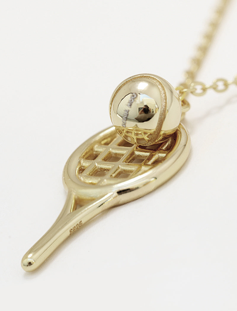 A silver tennis racket pendant necklace with a small silver tennis ball resting on the racket head, shown on a clean white background by Sonia Hou, a celebrity AAPI inclusive demi-fine jewelry designer. Available in 18K Gold Over Sterling Silver, Sterling Silver and 18K Gold PVD Stainless Steel (Waterproof).