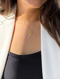 A close-up of a woman wearing a delicate gold tennis racquet ball chain necklace, styled with a white blazer and black top. Designed by Sonia Hou, a celebrity AAPI inclusive demi-fine jewelry designer. Available in 18K Gold Over Sterling Silver, Sterling Silver and 18K Gold PVD Sterling Silver (Waterproof).