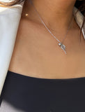 A close-up of a person's neck and chest wearing a delicate silver chain necklace with a tennis racket pendant and a tennis ball. Designed by Sonia Hou, a celebrity AAPI inclusive demi-fine jewelry designer. Available in 18K Gold Over Sterling Silver, Sterling Silver and 18K Gold PVD Sterling Silver (Waterproof).