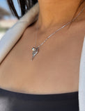 A close-up of a person wearing a delicate silver chain necklace with a small silver tennis racquet and ball pendant, styled with a light-colored blazer. Designed by Sonia Hou, a celebrity AAPI inclusive demi-fine jewelry designer. Available in 18K Gold Over Sterling Silver, Sterling Silver and 18K Gold PVD Sterling Silver (Waterproof).