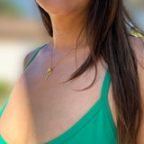 A close-up lifestyle shot of a woman wearing a delicate gold chain necklace with a tennis ball and racquet pendant, paired with a bright green tank top. Designed by Sonia Hou, a celebrity AAPI inclusive demi-fine jewelry designer. Available in 18K Gold Over Sterling Silver, Sterling Silver and 18K Gold PVD Sterling Silver (Waterproof).