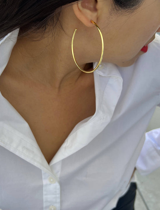 Female model wearing big medium large thin round circle PERFECT 50mm or 2 inch hoop stacking lightweight everyday statement earrings in 18K gold vermeil with a 925 Sterling Silver base by Sonia Hou, a celebrity AAPI Chinese demi-fine jewelry designer